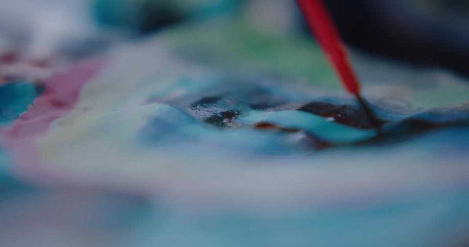 A red paintbrush brushing paint onto a piece of paper