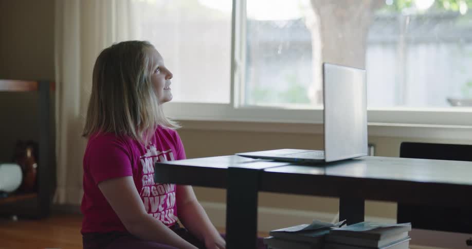 A young girl at home talks with someone on a laptop