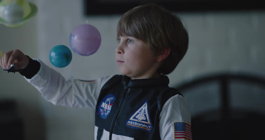 A child with a nasa jacket is playing with a toy