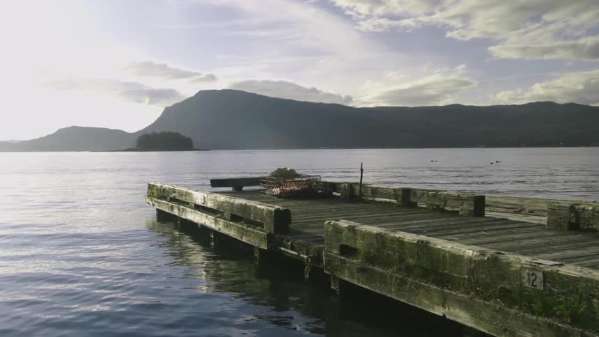 A low pier extending out on a lake at sunset on a partly cloudy day