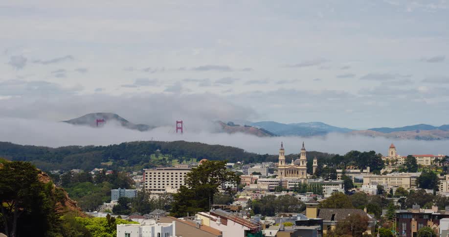 Small town on the hills near a suspension bridge covered in mist close to the mountains