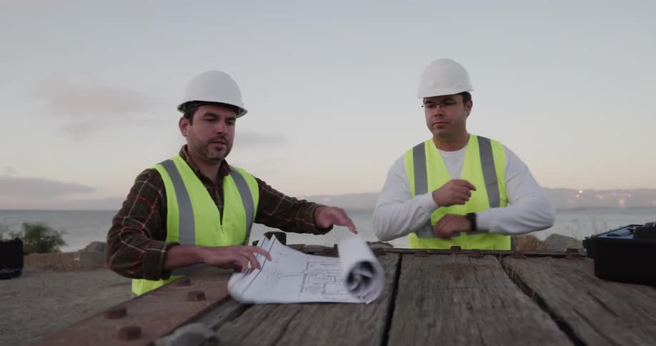 Two construction workers roll out blueprints