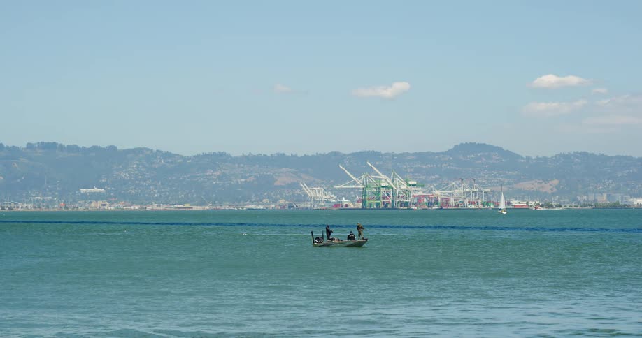 Three people in a boat on the water with a skyline in the distance