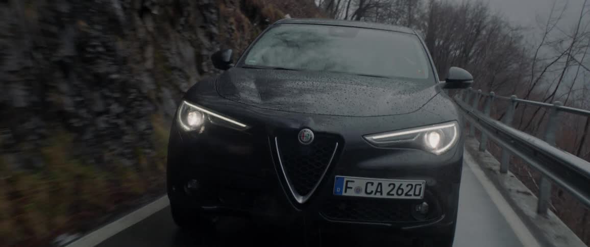 A car drives on a rural road in the rain