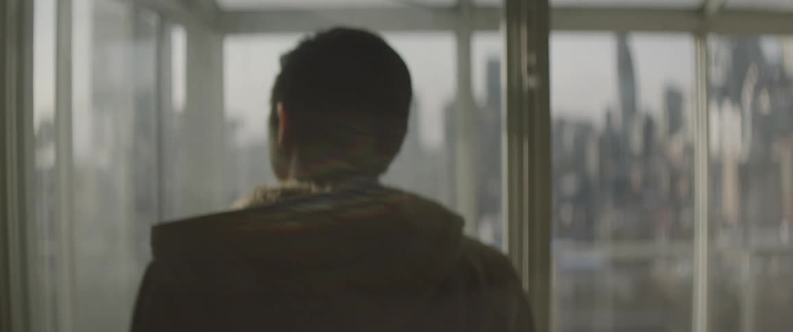 A man in a jacket walks up to a window