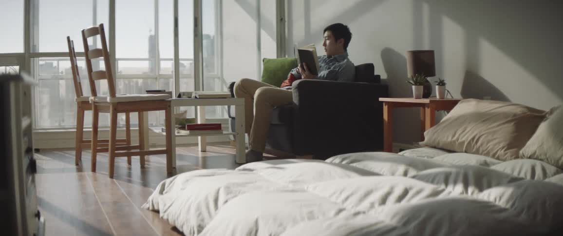 Man sitting on couch in home reading a book picks up cell phone