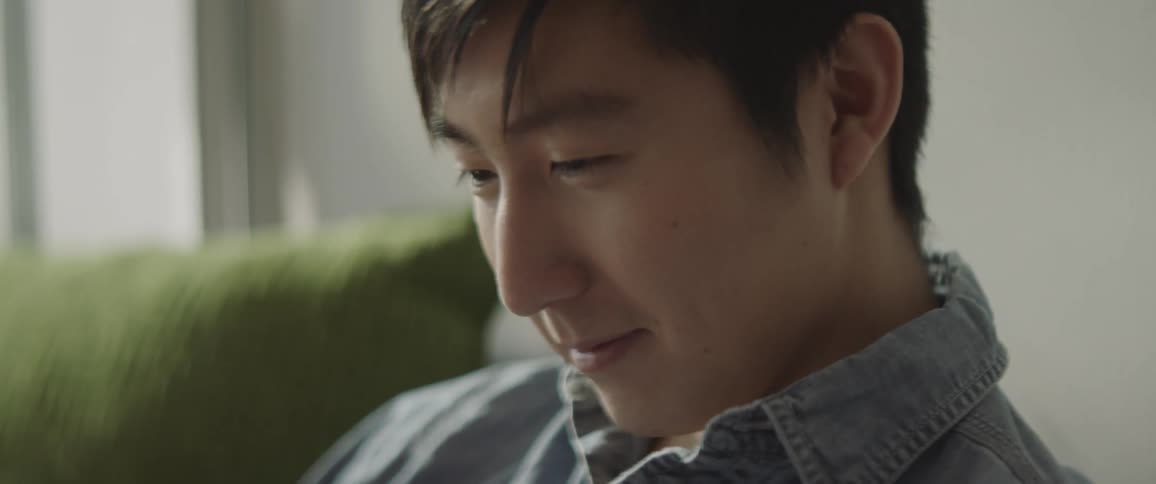 A man smiles while sitting on a couch