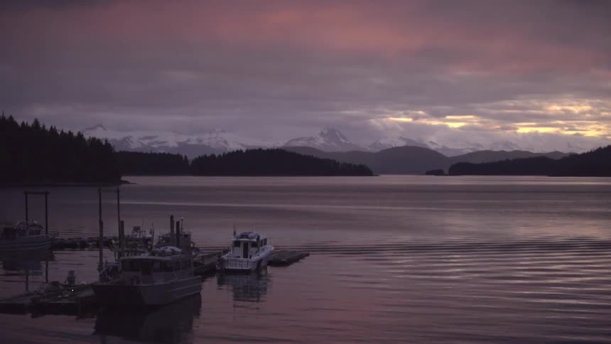 A few boats are docked on a large lake at dusk