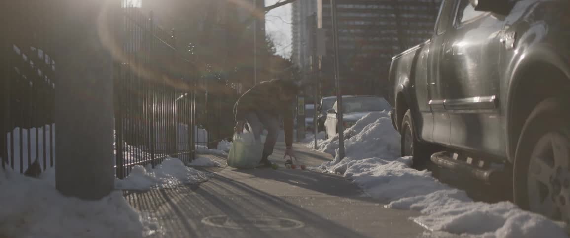 A man drops his groceries and picks them up in a hurry