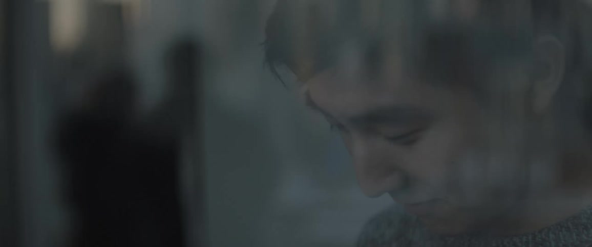 A man stands by the window using his phone