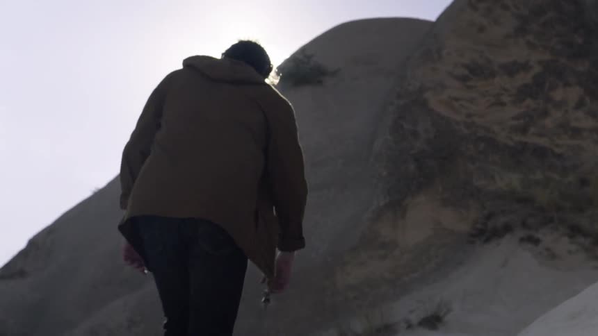 A man climbs up a hill on sunny day