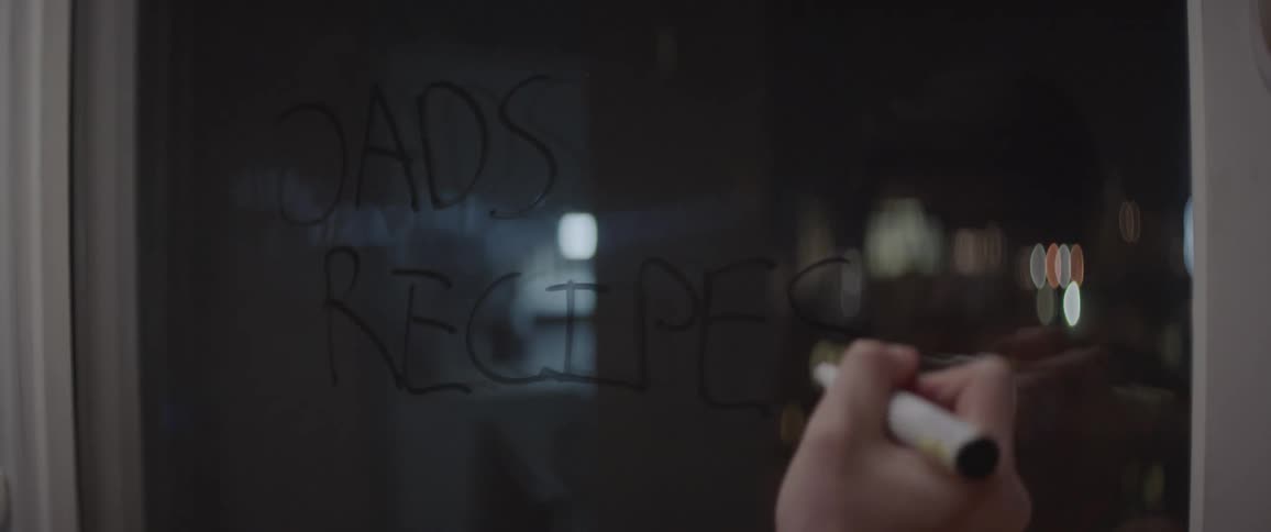A man writes on a window with a marker