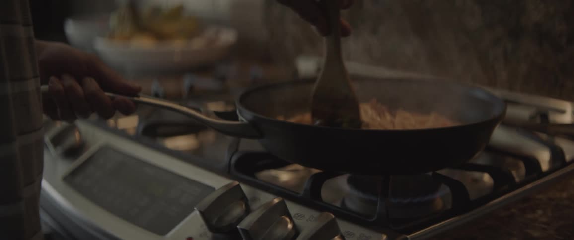 A man is mixing spaghetti in a pan