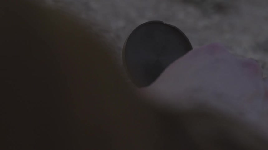 A hand picks up a compass from the ground