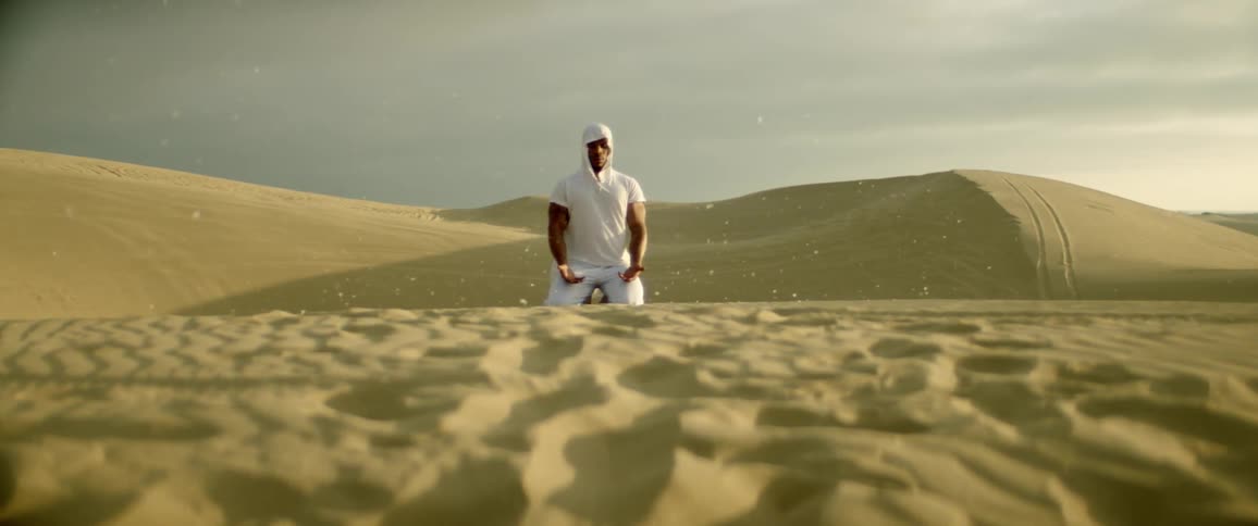 A man kneels in a sandy desert
