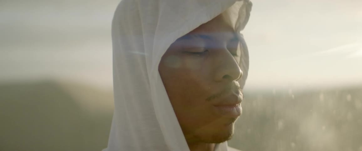 Man prays in an empty desert as sand blows past him