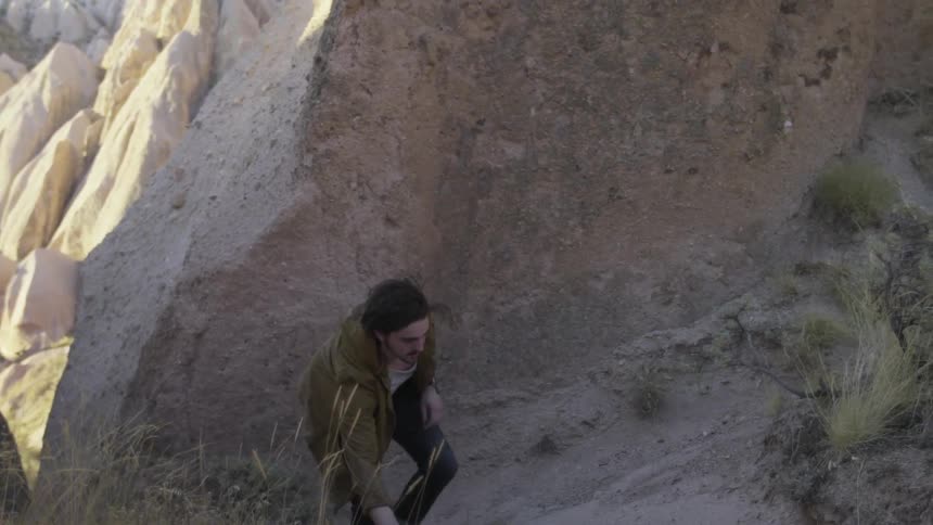 A man is climbing uphill between some large rocks