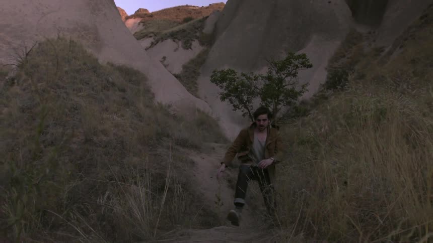 A man is climbing uphill between some rocks