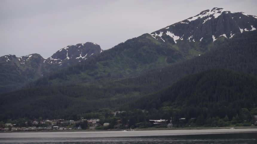 A small airplane flies over a mountain lake