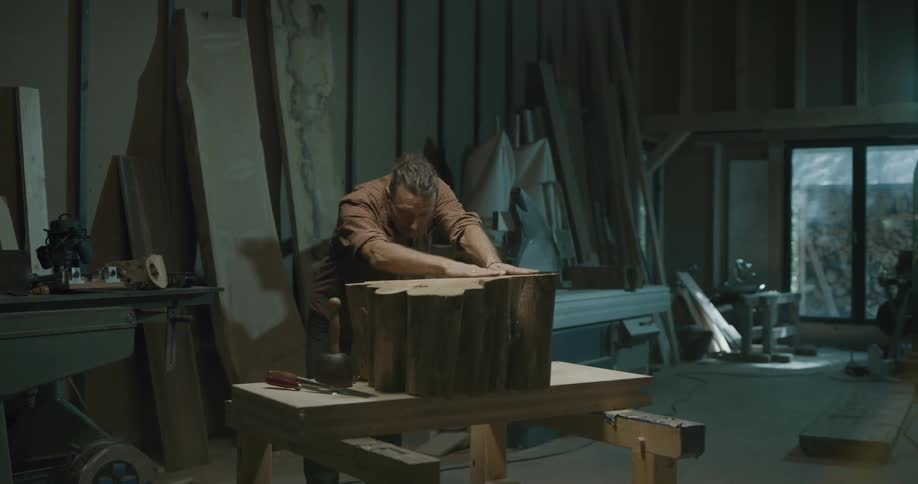 Man examines smoothness of current woodworking project in workshop