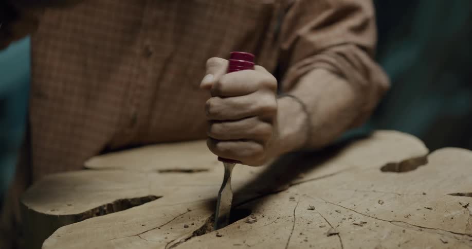 A man carving wood out of a tree trunk