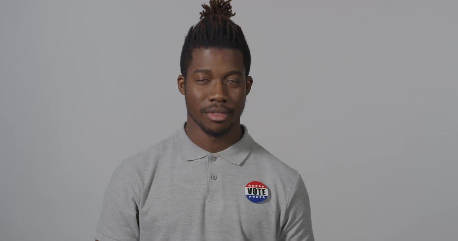 Standing man pins on a vote button then smiles