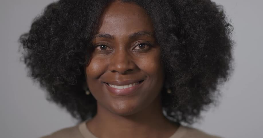 Black woman with curly hair looks and beams at the camera