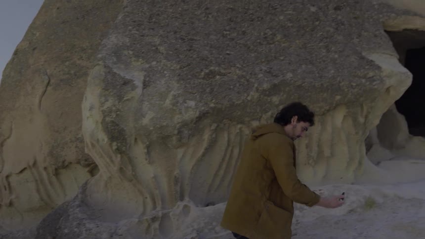 A man walks uphill near a cavern