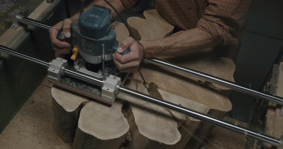 A man runs a tool across a tree stump as he builds something