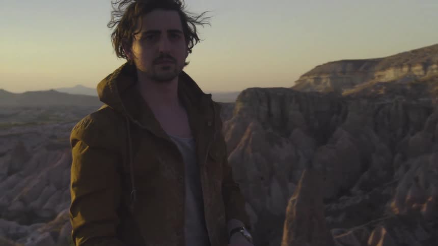 A man stands on a mountain in the morning