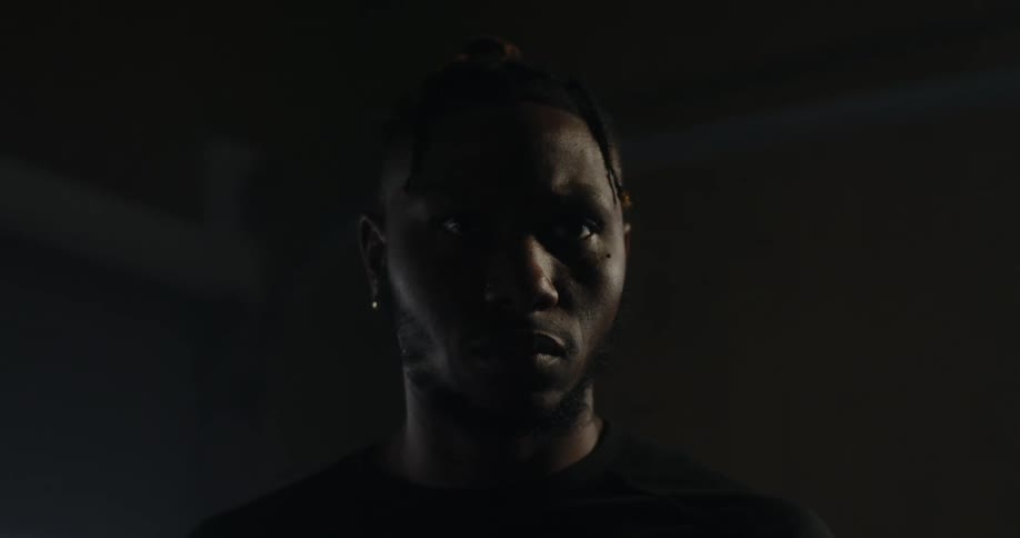 A black man standing in a dark room
