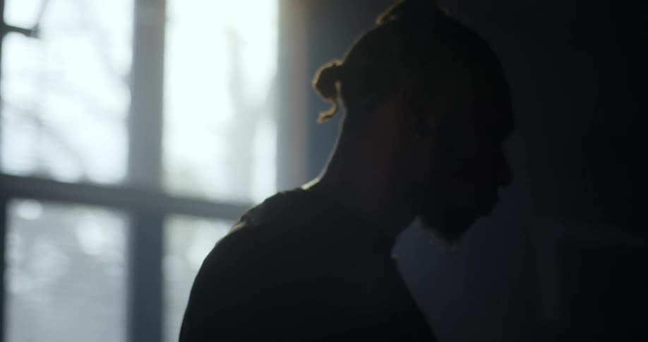 A black man standing in a dark room