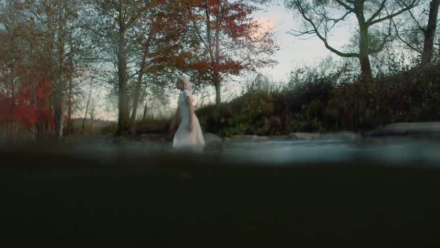 Woman enters a stream and walks towards a man standing in the stream