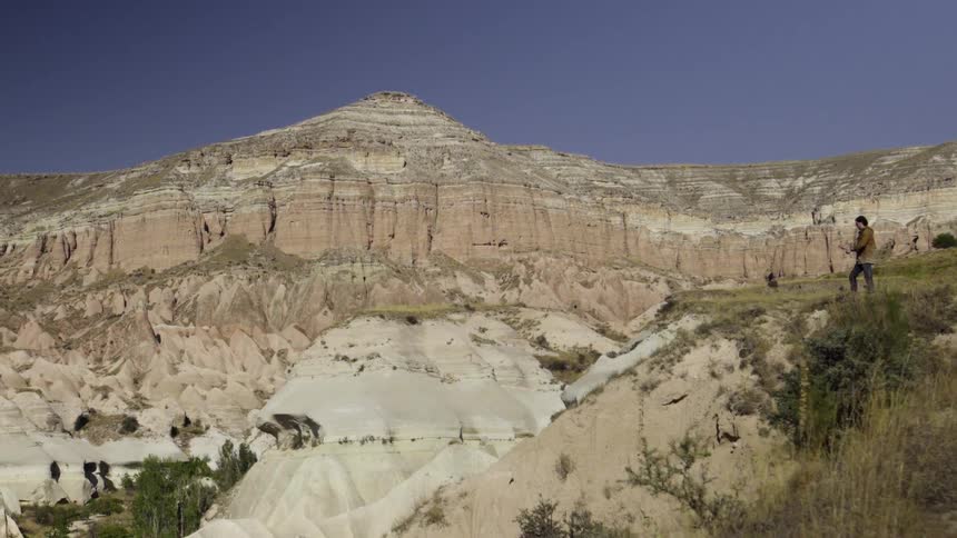 A man is standing on a hill near a mountain