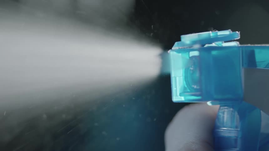 A man spraying liquid out of a bottle in to the air