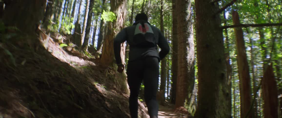 A man jogs up a forest trail