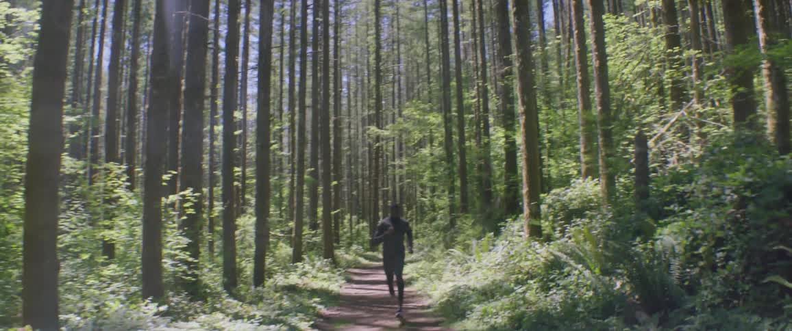A man is running down a path in the forest