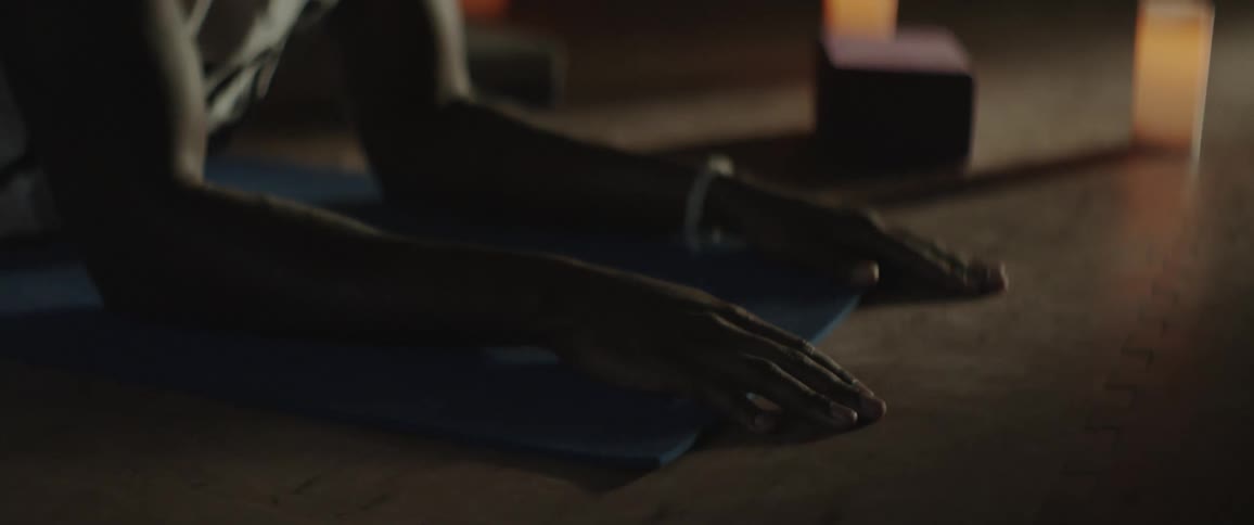 A male athlete is resting in a yoga pose in a dark room