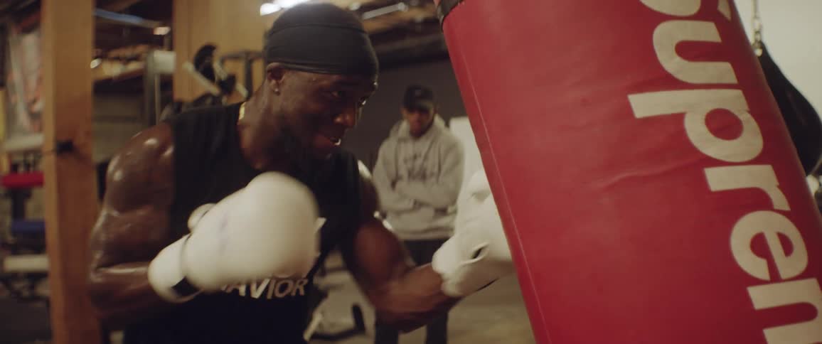 A man is using white boxing gloves punching a heavy bag