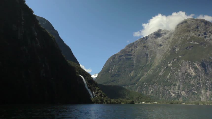 A waterfall pours down a wooded hill