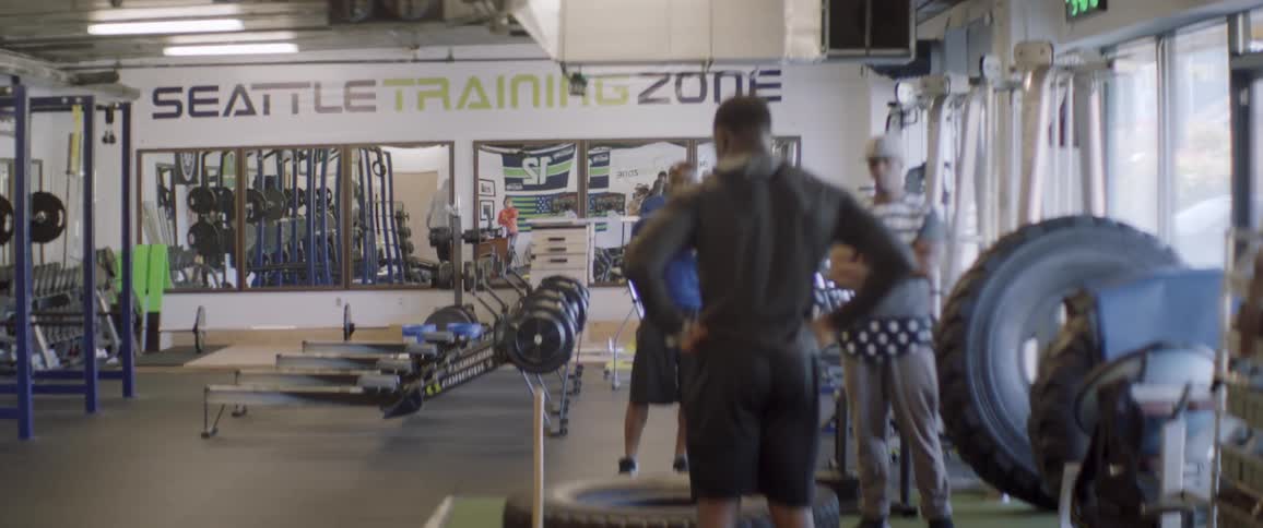 Man pounds a large tire with a hammer in a gym