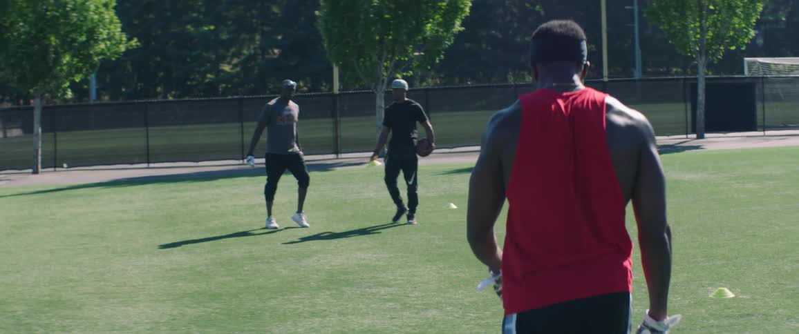 An athlete points and walks towards a man holding a football