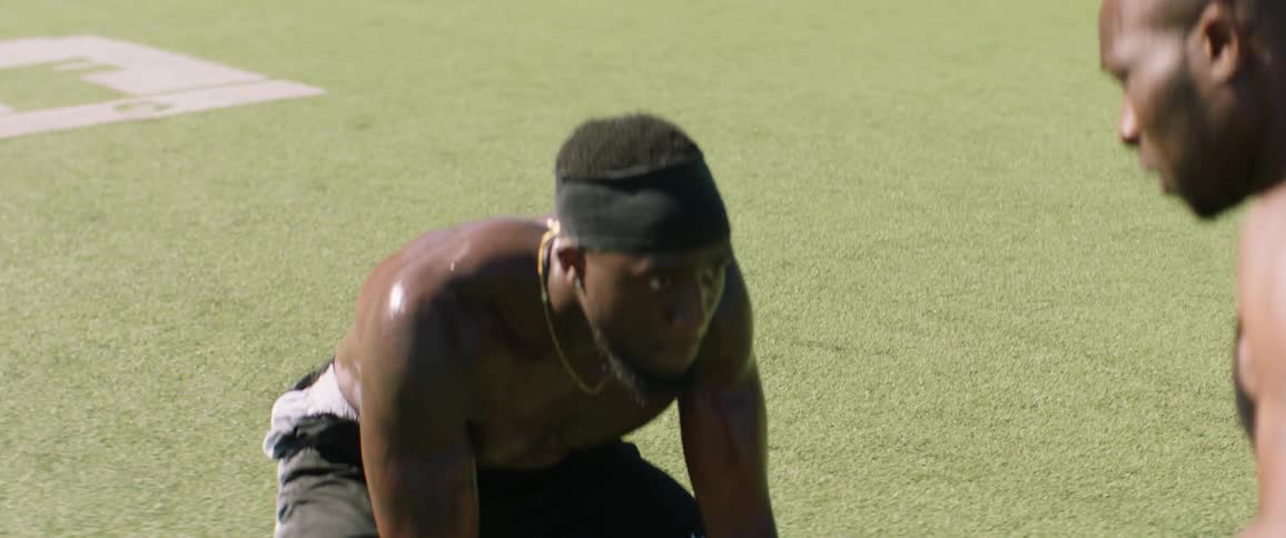 Football players run drills outside on a sunny day