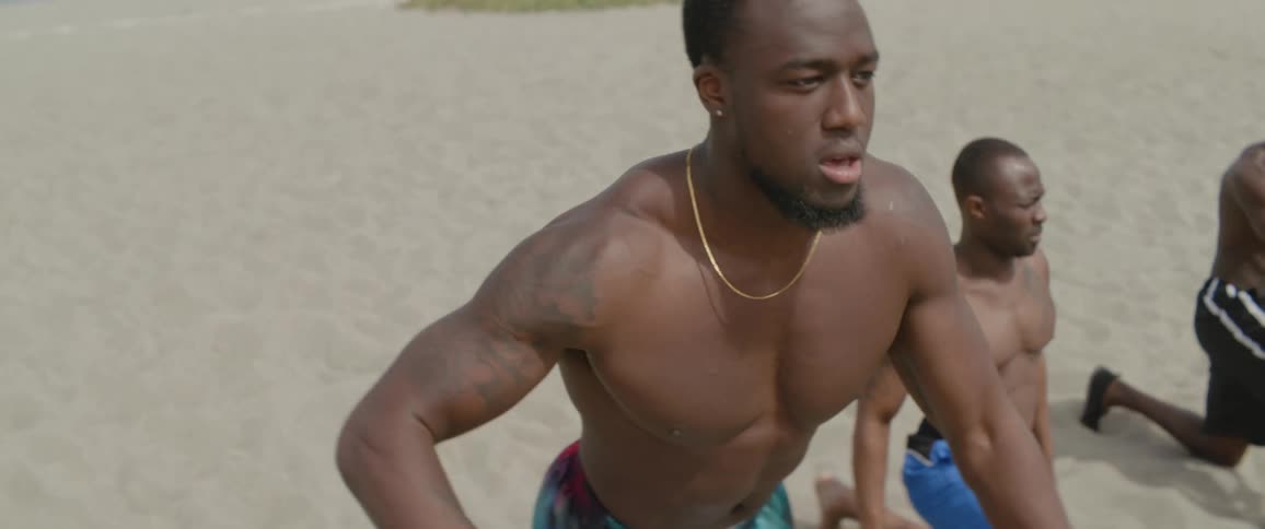 Three men exercise on the beach