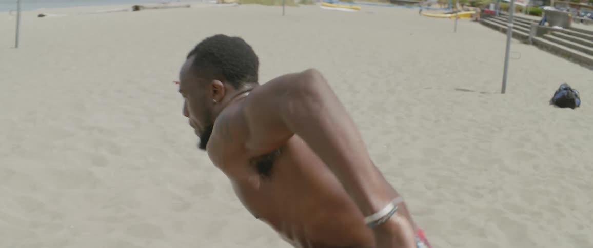 Shirtless man sprints back and forth in the sand