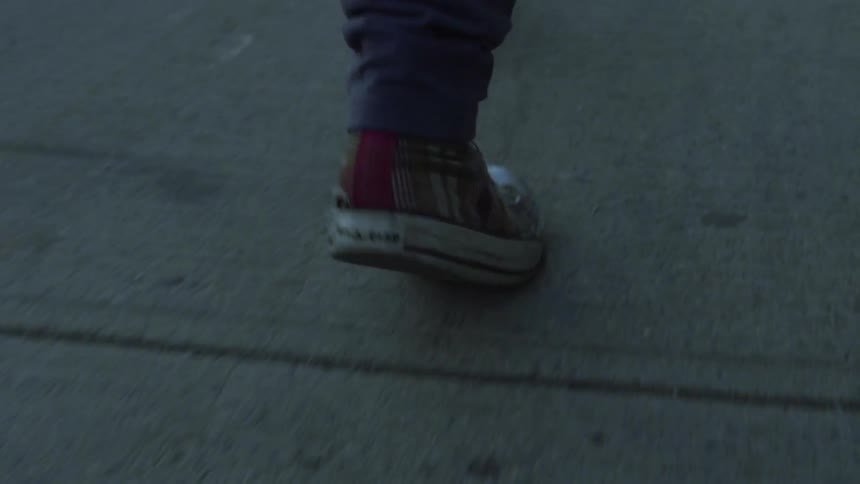 View of a person's shoes as they walk along a sidewalk