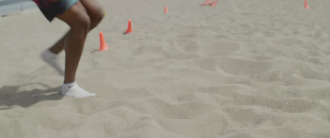 A man is running back and forth in the sand
