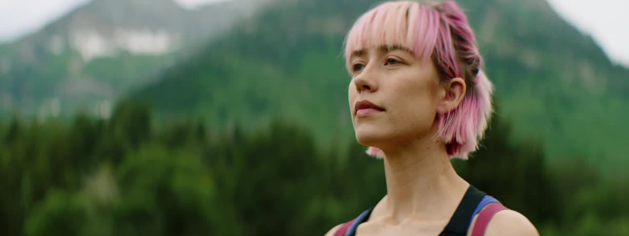 A young woman takes deep breaths while standing outdoors during the day