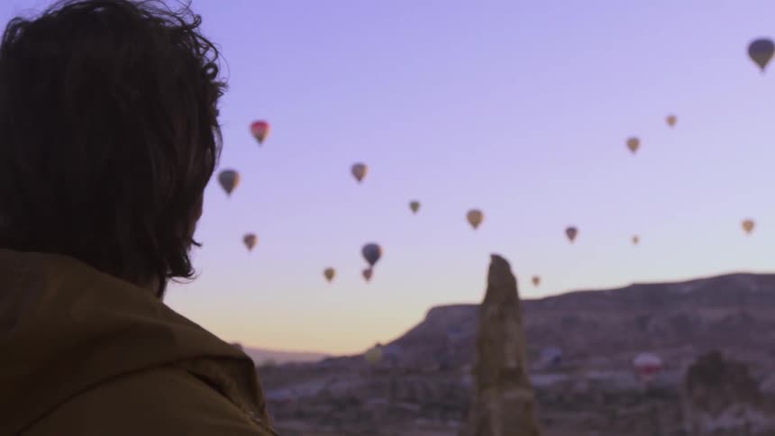 A man watches a sky full of hot air balloons