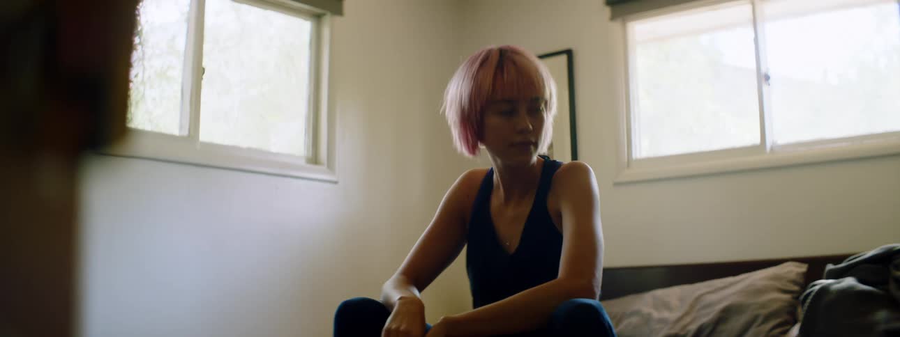 A teenage girl sits on her bed and dances